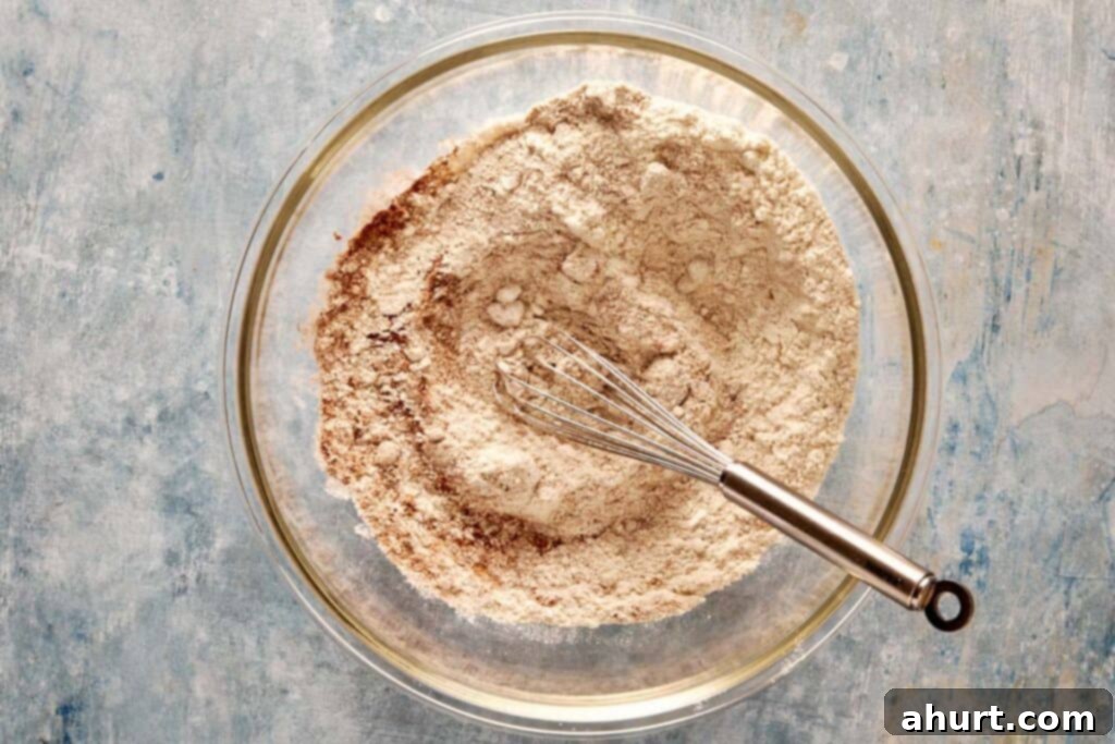A top-down view of a glass bowl showcasing all the dry ingredients perfectly combined, with a metal whisk elegantly resting on the side.