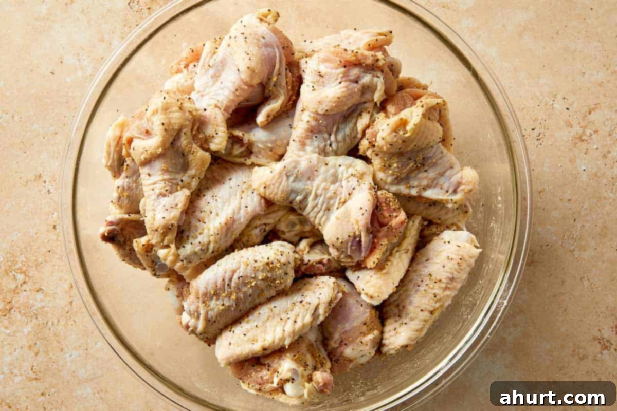 Lemon Pepper Wings: A Zesty Bite of Sunshine 6 Raw chicken wings tossed with lemon pepper seasoning and baking powder in a bowl, evenly coated before cooking