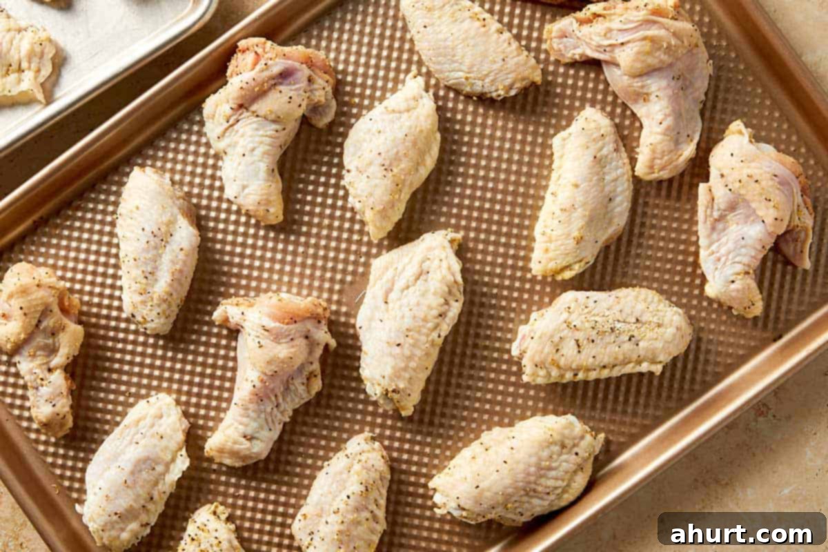 Lemon Pepper Wings: A Zesty Bite of Sunshine 7 Seasoned lemon pepper chicken wings arranged in a single layer on a baking tray, spaced apart for even cooking and crisping
