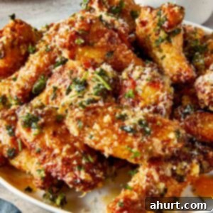 garlic parmesan chicken wings on plate with crispy skin, melted butter, parmesan cheese and fresh parsley